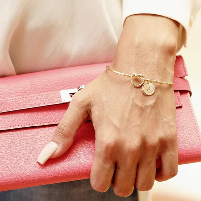 Gold knot pendant bracelet on white background