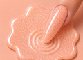 Close-up of a hand with glittery pink nail polish on a matching pink background